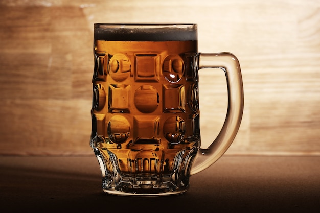 Foto grátis copo de cerveja sobre a superfície de madeira
