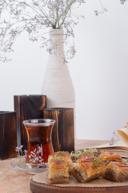 Copo de chá e baklava de pistache tradicional na mesa de mármore.