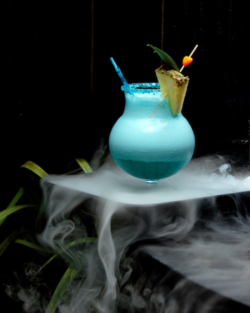 copo de cocktail azul espumoso, guarnecido com fatia de abacaxi