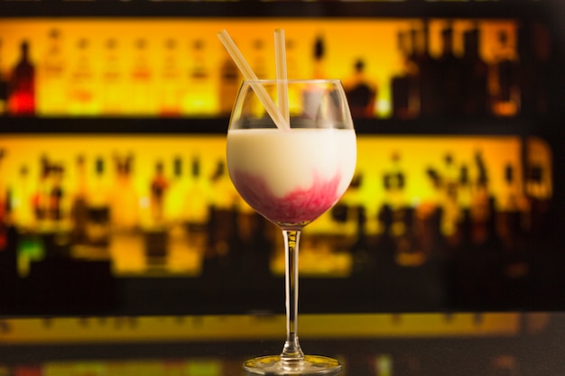 Foto grátis copo de cocktail com garrafas no fundo