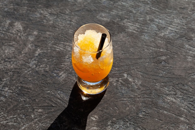 Copo de granizado de laranja em fundo escuro gelo picado com suco de laranja ou xarope de bebida