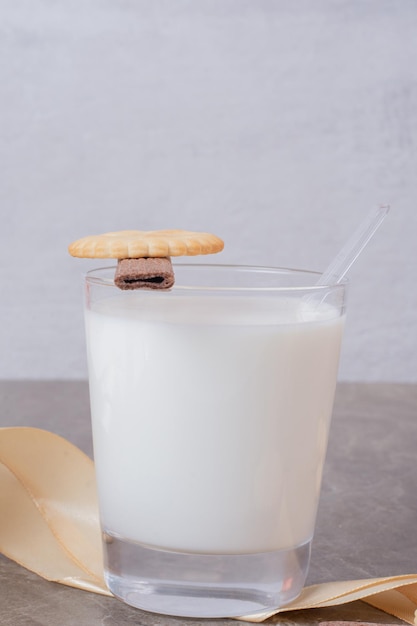 Copo de leite com biscoitos na mesa de mármore.