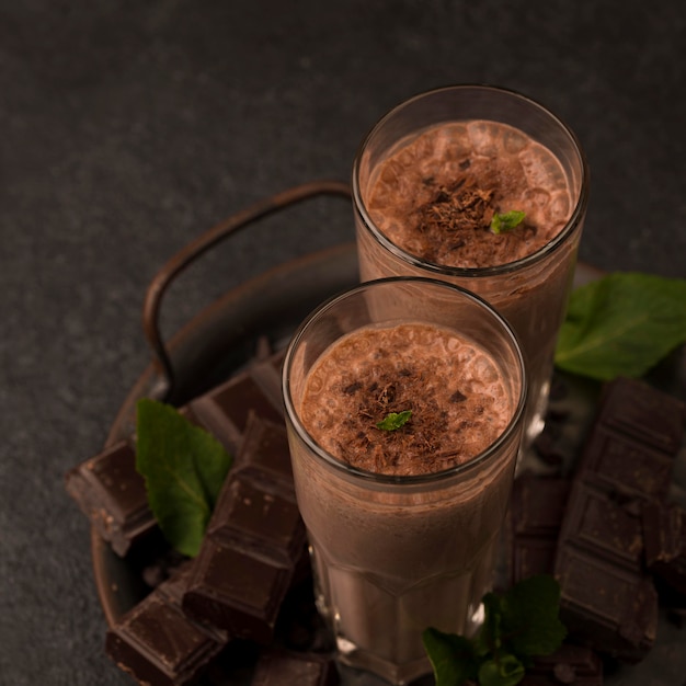 Copo de milkshake de ângulo alto na bandeja com hortelã e chocolate