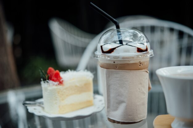 copo de plástico de café gelado com bolo na mesa na loja de café