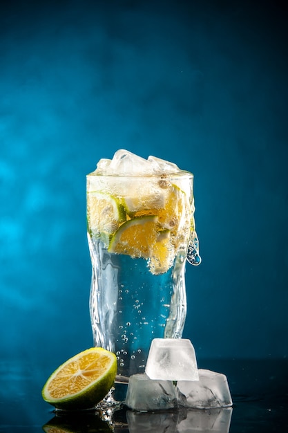 Copo de refrigerante com rodelas de limão e cubos de gelo em uma foto azul champanhe coquetel de água com limonada