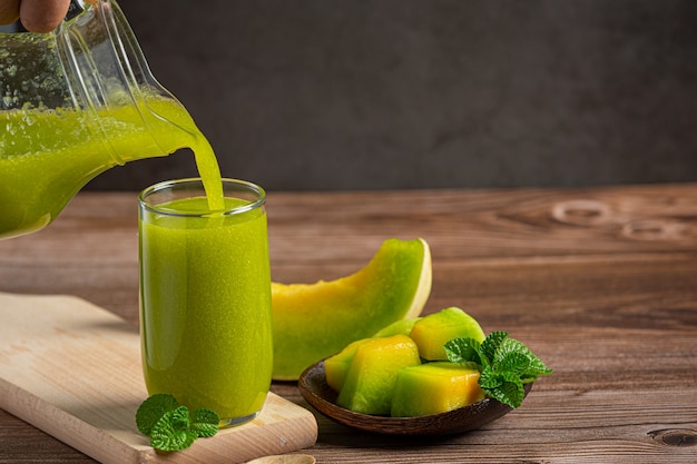 Foto grátis copo de suco de melão colocado no chão de madeira