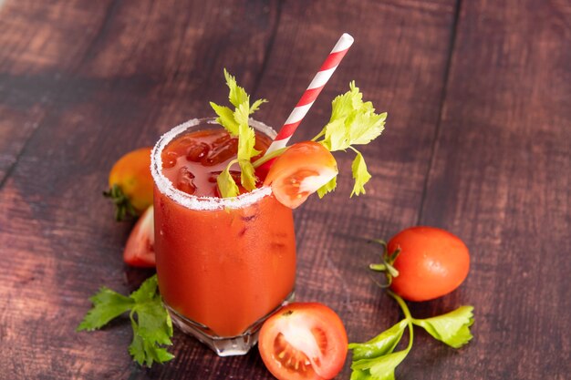 Copo de suco de tomate com tomates frescos brilhantes, salsa verde em um fundo escuro. bebida vegetal.