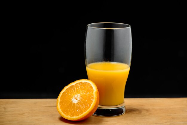 Copo de suco e meia laranja na mesa de madeira