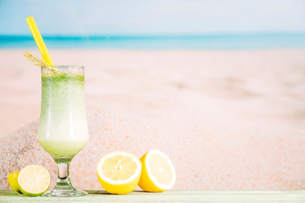 Foto grátis copo de suco verde fresco e fatias de frutas cítricas