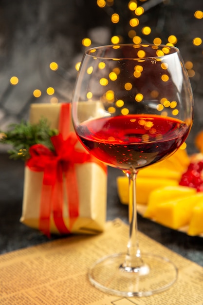 Copo de vinho de frente para presente de Natal em fundo escuro