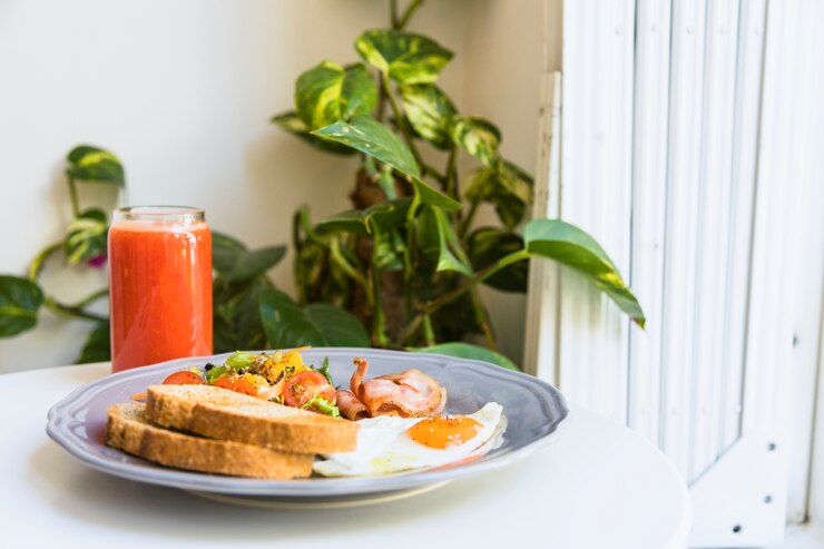 Foto grátis copo saudável de smoothies com bacon; salada; bacon e ovos fritos na placa cerâmica sobre a mesa branca