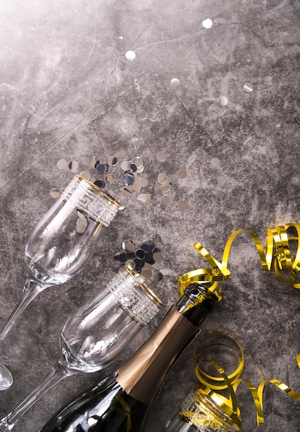 Copo vazio e garrafa de champanhe com item decorativo de festa no plano de fundo texturizado concreto