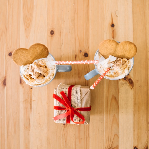 Foto grátis copos com bebida e biscoitos perto do presente