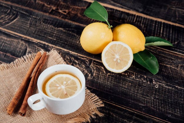 Copos de chá com limão, limões cortados em uma tábua de cortar