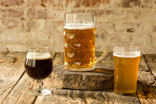 Copos de diferentes tipos de cerveja escura e clara na mesa de madeira em linha. Deliciosos drinks gelados preparados para a festa de um grande amigo. Conceito de bebidas, diversão, reunião, oktoberfest.