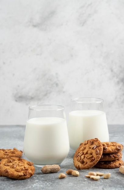 Copos de leite e biscoitos caseiros com amendoim orgânico na mesa de mármore.