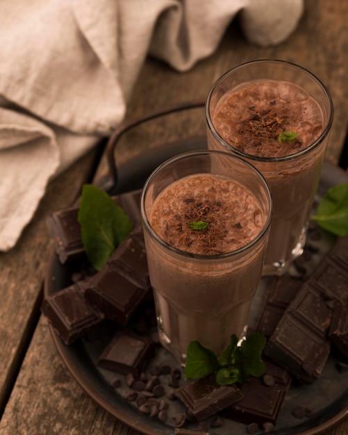 Copos de milkshake de chocolate em ângulo alto na bandeja com hortelã