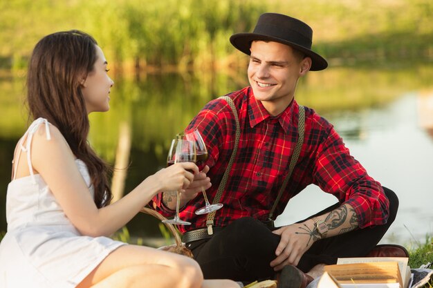 Copos tilintando. Casal jovem e feliz caucasiano, aproveitando o fim de semana juntos no parque num dia de verão.