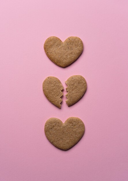 Coração de biscoito quebrado leigo plano no fundo rosa