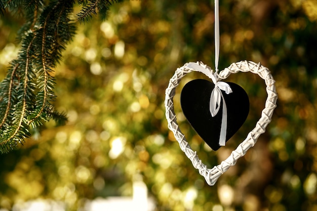 Coração preto colocado no coração branco pendurado na árvore