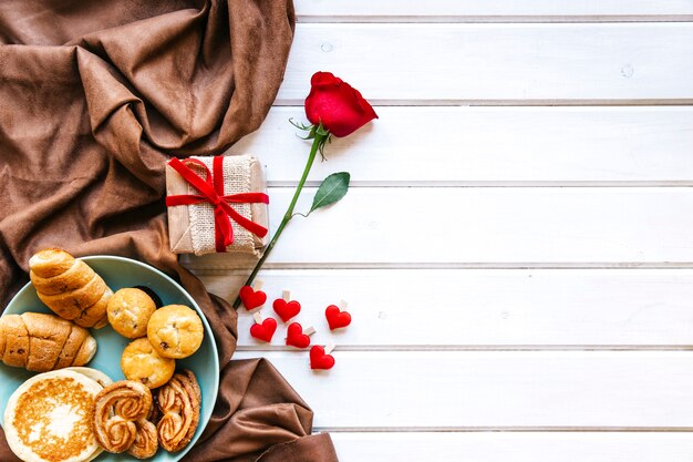 Corações e rosa perto de presente e pastelaria