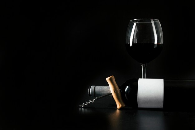 Corkscrew e garrafa perto de wineglass