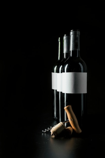 Corkscrew e rolhas perto de garrafas de vinho