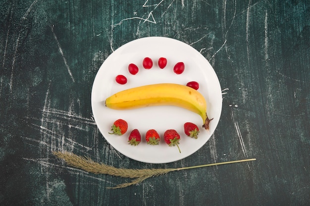 Foto grátis cornel, morango e banana em um prato branco no centro