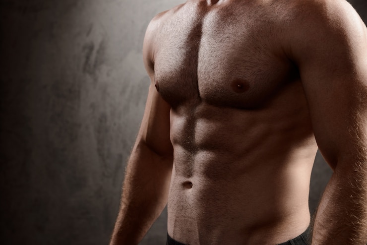 Foto grátis corpo do homem esportivo sobre parede escura.
