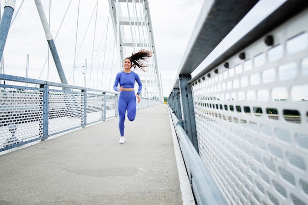 Corredor feminino com corpo forte e pernas correndo pela ponte e treinando