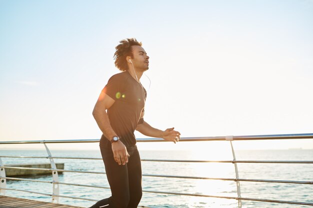 Corredor no sportswear fazendo treino cardio na praia pela manhã