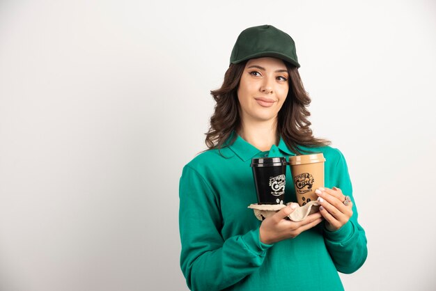 Correio feminino de uniforme segurando xícaras de café.