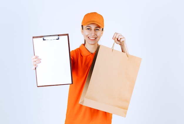 Correio feminino em uniforme amarelo entregando uma sacola de compras e apresentando a lista de assinaturas.