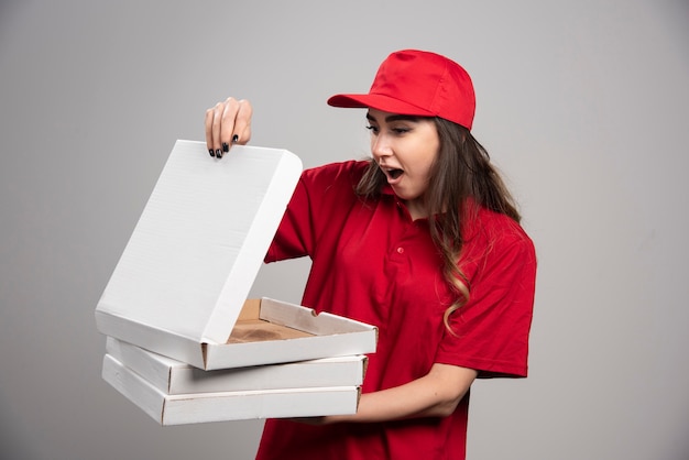 Foto grátis correio feminino olhando para a caixa de pizza vazia.