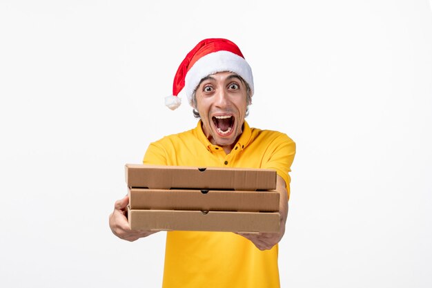 Correio masculino de vista frontal com caixas de pizza em trabalho de serviço de entrega uniforme de parede branca