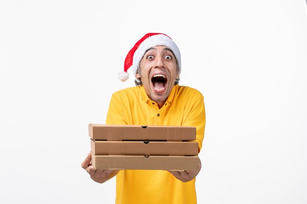 Correio masculino de vista frontal com caixas de pizza na entrega de serviço uniforme de trabalho de parede branca