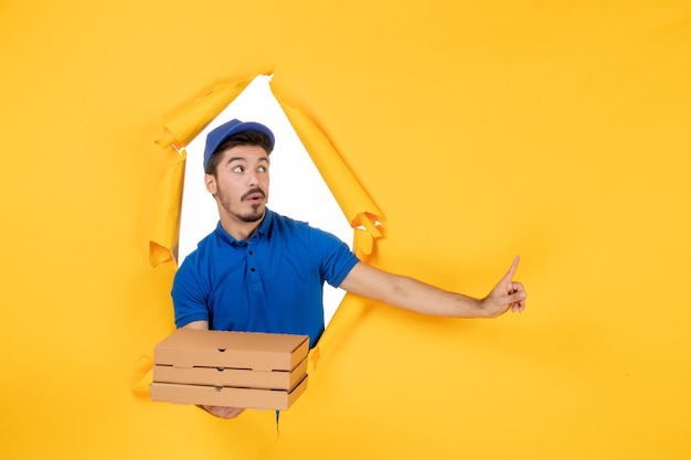 Correio masculino de vista frontal segurando caixas de pizza no espaço amarelo