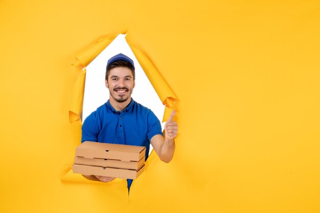 Correio masculino de vista frontal segurando caixas de pizza no espaço amarelo