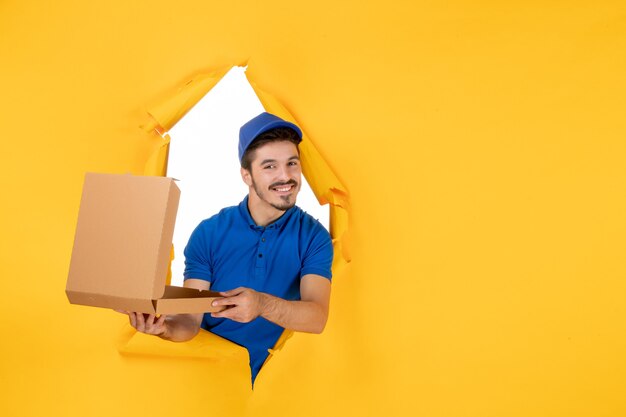 Correio masculino de vista frontal segurando uma caixa de pizza aberta no espaço amarelo