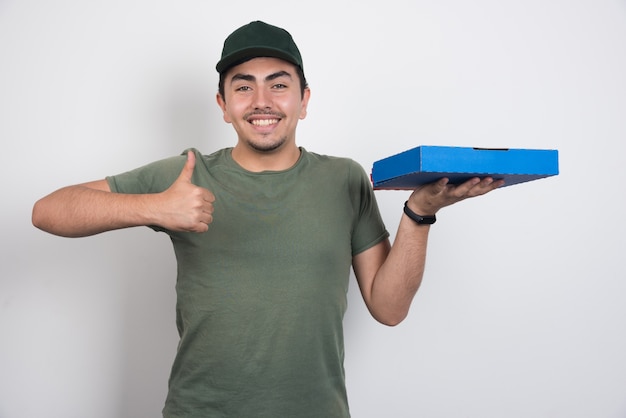 Foto grátis correio positivo segurando pizza e mostrando os polegares em fundo branco.