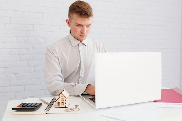 Corretor de imóveis usando o laptop no local de trabalho