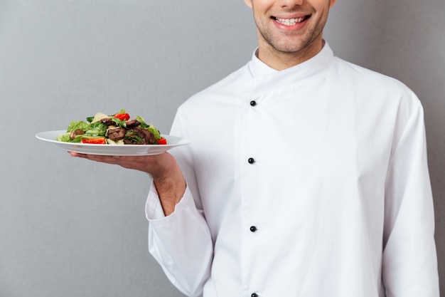 Cortada a imagem de um chef masculino sorridente, vestido de uniforme