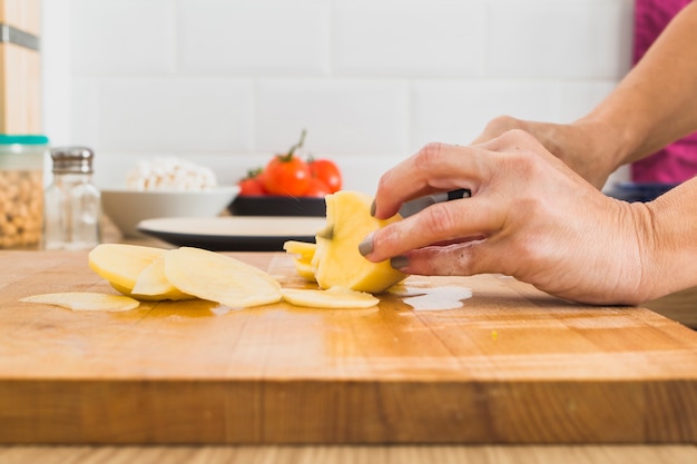 Cortar as mãos cortando batata a bordo