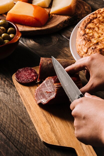 Cortar as mãos cortar carne defumada perto de comida