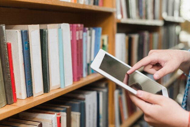 Cortar as mãos usando tablet na biblioteca