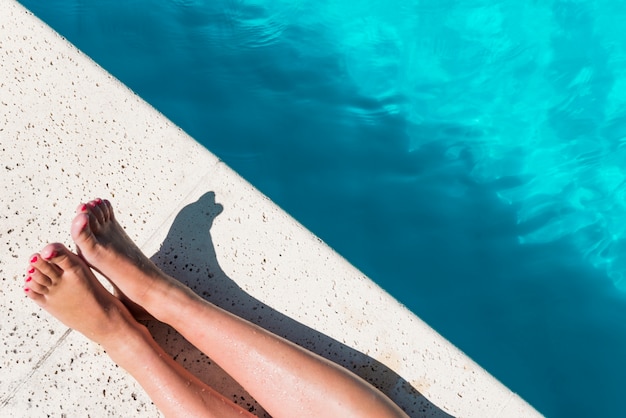 Cortar as pernas femininas na beira da piscina