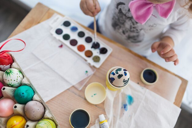Cortar criança pintando ovos com aquarela