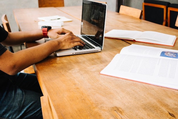 Cortar homem estudando com laptop perto de livros