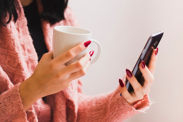 Foto grátis cortar mulher com smartphone desfrutando de bebida