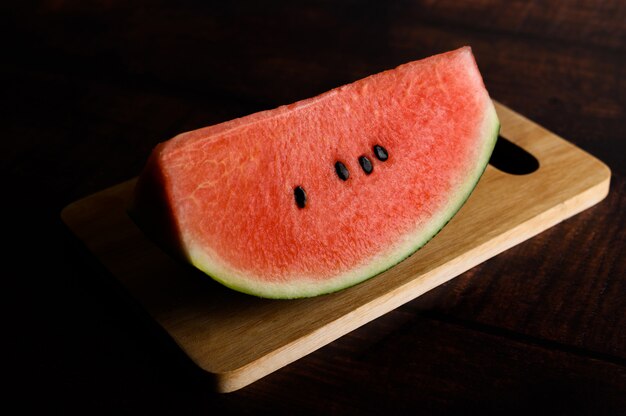 Corte a melancia em tábuas sobre uma mesa de madeira.